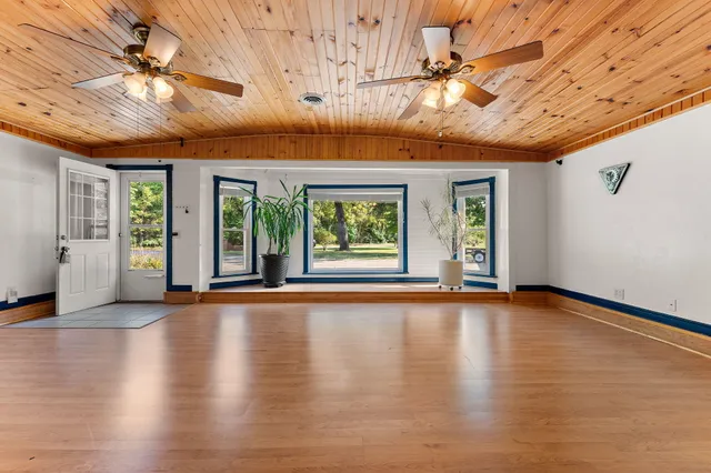 a view of an empty room with wooden floor and windows