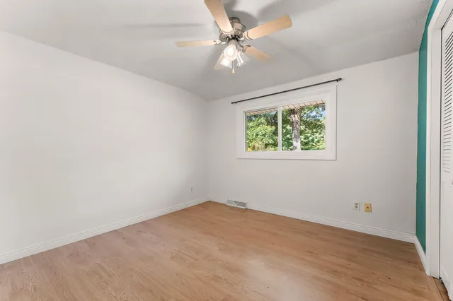 an empty room with a window and a fan