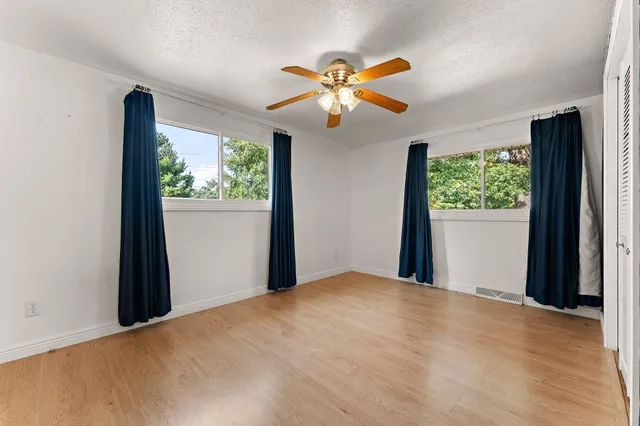 a view of a big room with windows and chandelier fan