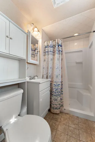 a bathroom with a granite countertop toilet a sink and a shower