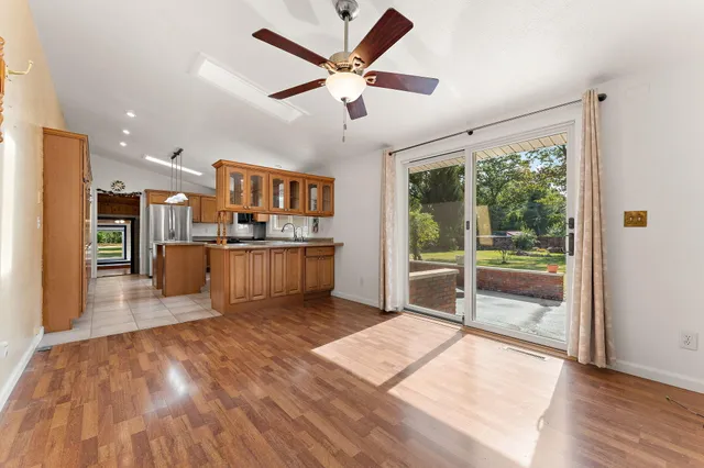 a living room with stainless steel appliances kitchen island granite countertop a refrigerator a stove and a wooden floors