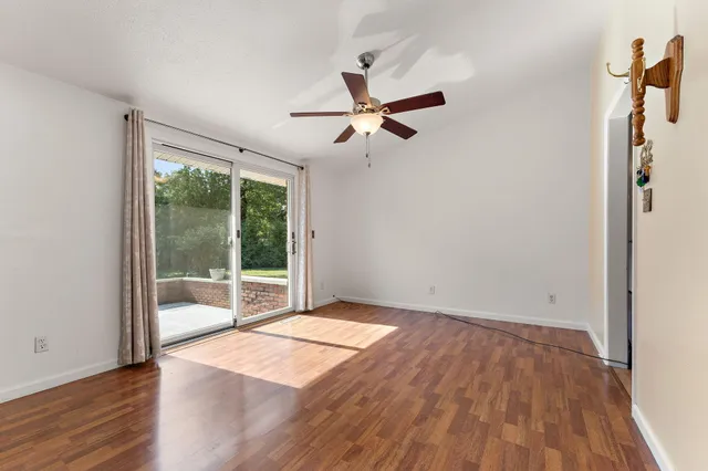 a view of an empty room with wooden floor and a window