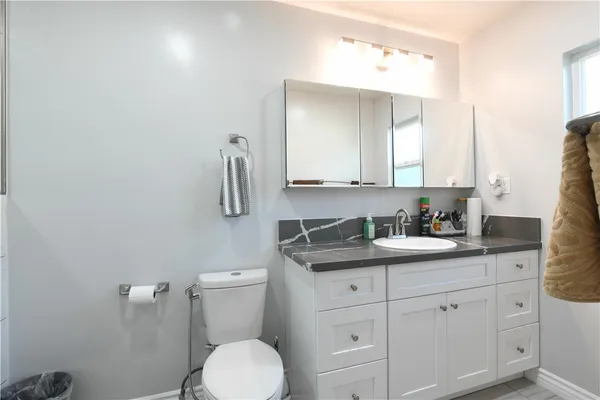 a bathroom with a granite countertop toilet sink and mirror