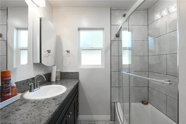 a bathroom with a granite countertop sink a mirror and shower
