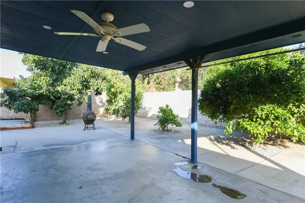a view of a patio with a table and chairs under an umbrella with a large tree