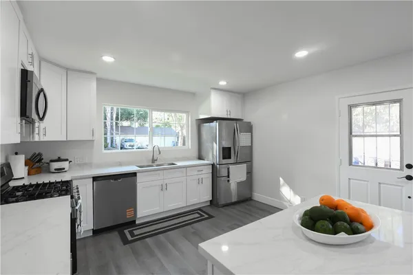 a kitchen with stainless steel appliances a sink a stove a refrigerator cabinets and a window