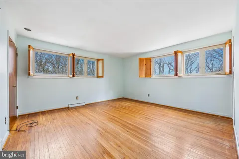 a view of an empty room with window and wooden floor