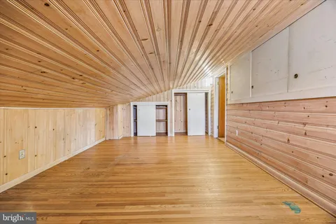 a view of an empty room with wooden floor and entryway