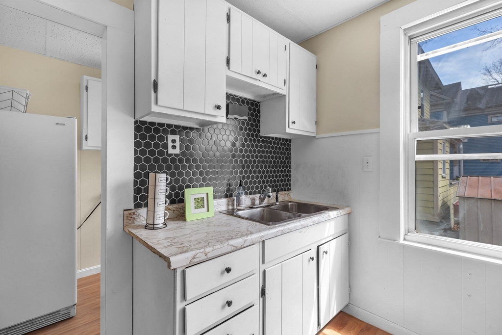 102 Florida Street Springfield, MA 01109 - Photo 5 of 45 a kitchen with stainless steel appliances granite countertop a sink dishwasher a refrigerator and white cabinets with wooden floor