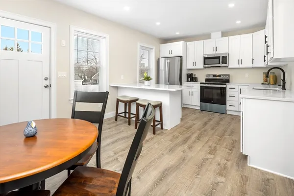 a kitchen with stainless steel appliances granite countertop a stove a refrigerator a kitchen island with a dining table and chairs