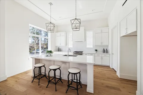 a view of a kitchen with kitchen island a sink wooden floor and living room view