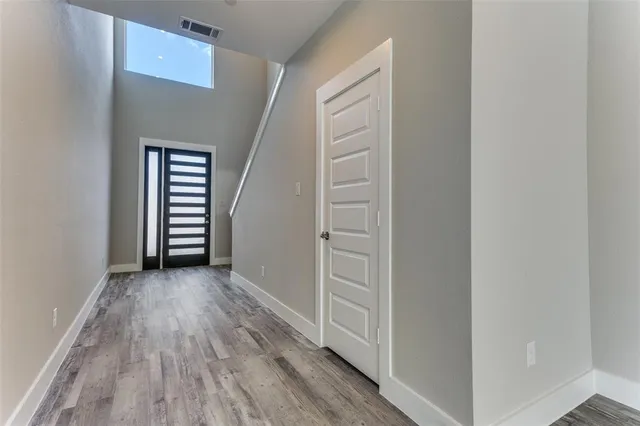 a view of an empty room with wooden floor and a kitchen