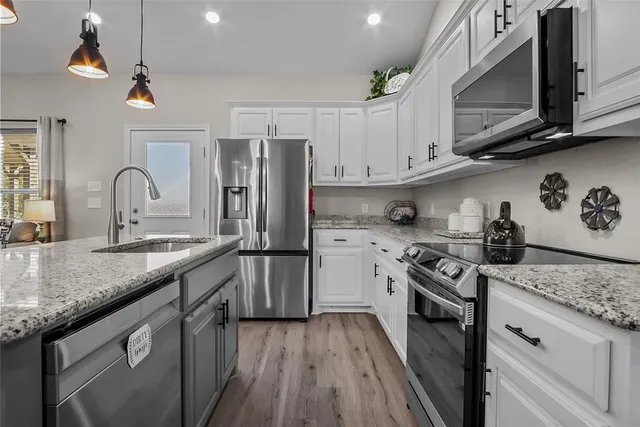 a kitchen with stainless steel appliances granite countertop a sink dishwasher stove and refrigerator with wooden floor