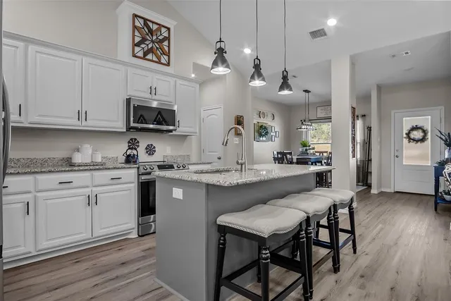 a kitchen with kitchen island granite countertop a sink a counter space stainless steel appliances and cabinets