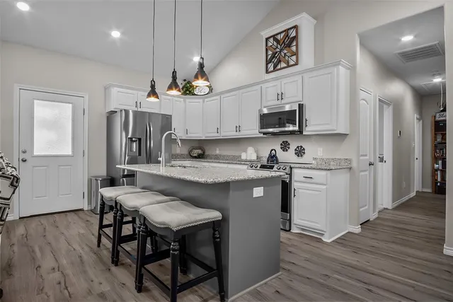 a kitchen with kitchen island granite countertop a sink cabinets and wooden floor