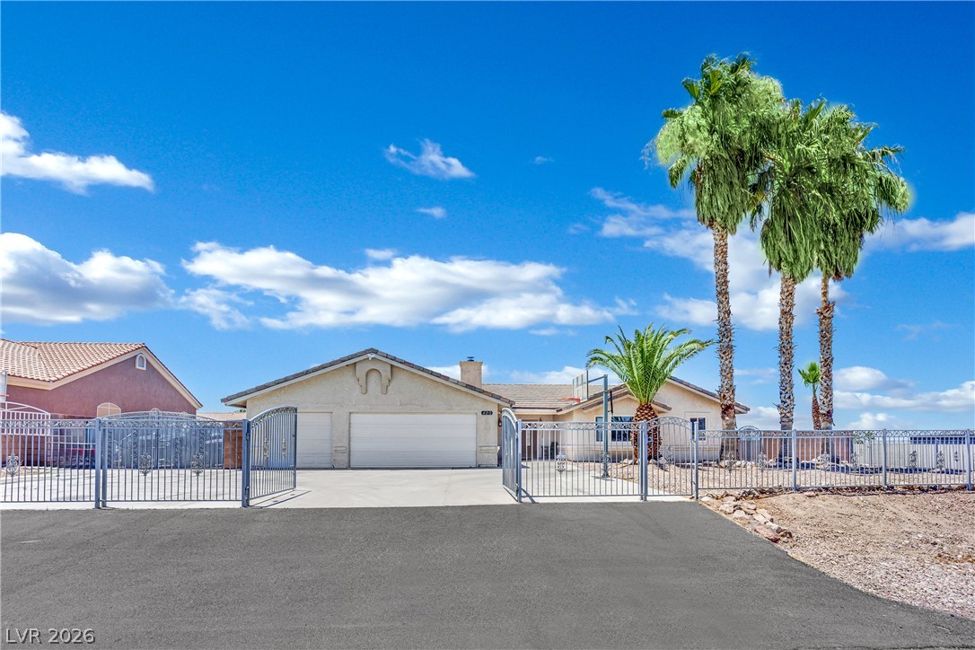 420 North Racetrack Road Henderson, NV 89015 - Photo 2 of 52 A private gate opens to a desert oasis featuring mature palm trees and a two-car garage.