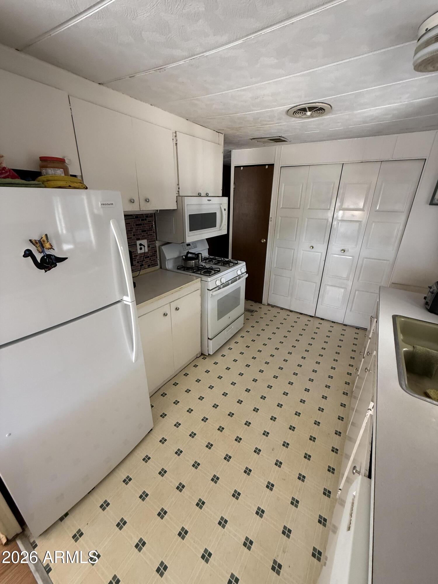 9501 East Broadway Road, Unit 164 Mesa, AZ 85208 - Photo 11 of 27 a kitchen with a sink a refrigerator and cabinets