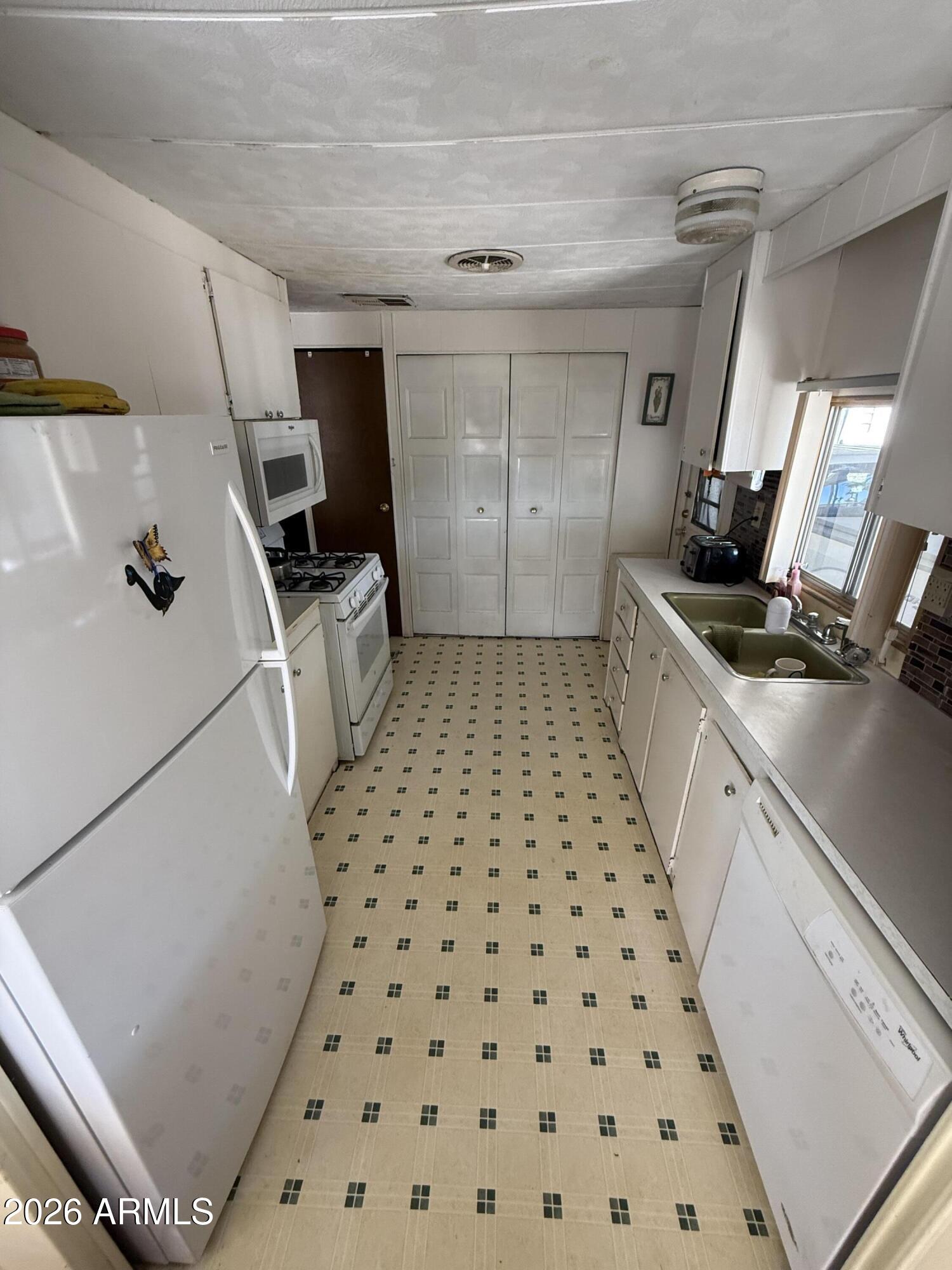 9501 East Broadway Road, Unit 164 Mesa, AZ 85208 - Photo 10 of 27 a kitchen with granite countertop a sink a stove a refrigerator and cabinets