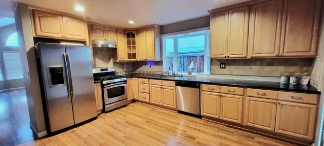 a kitchen with granite countertop stainless steel appliances a sink cabinets and a window