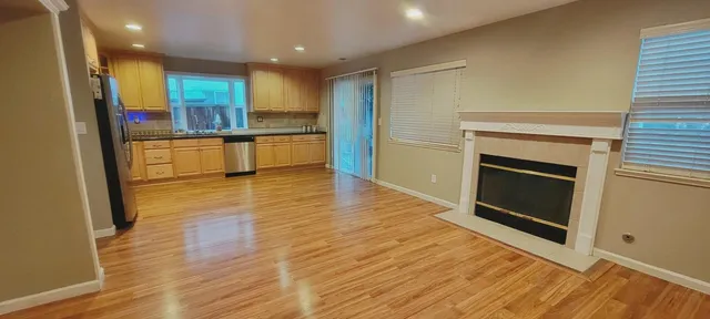 a view of kitchen with kitchen island wooden floor and stainless steel appliances