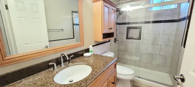 a bathroom with a granite countertop sink toilet and shower