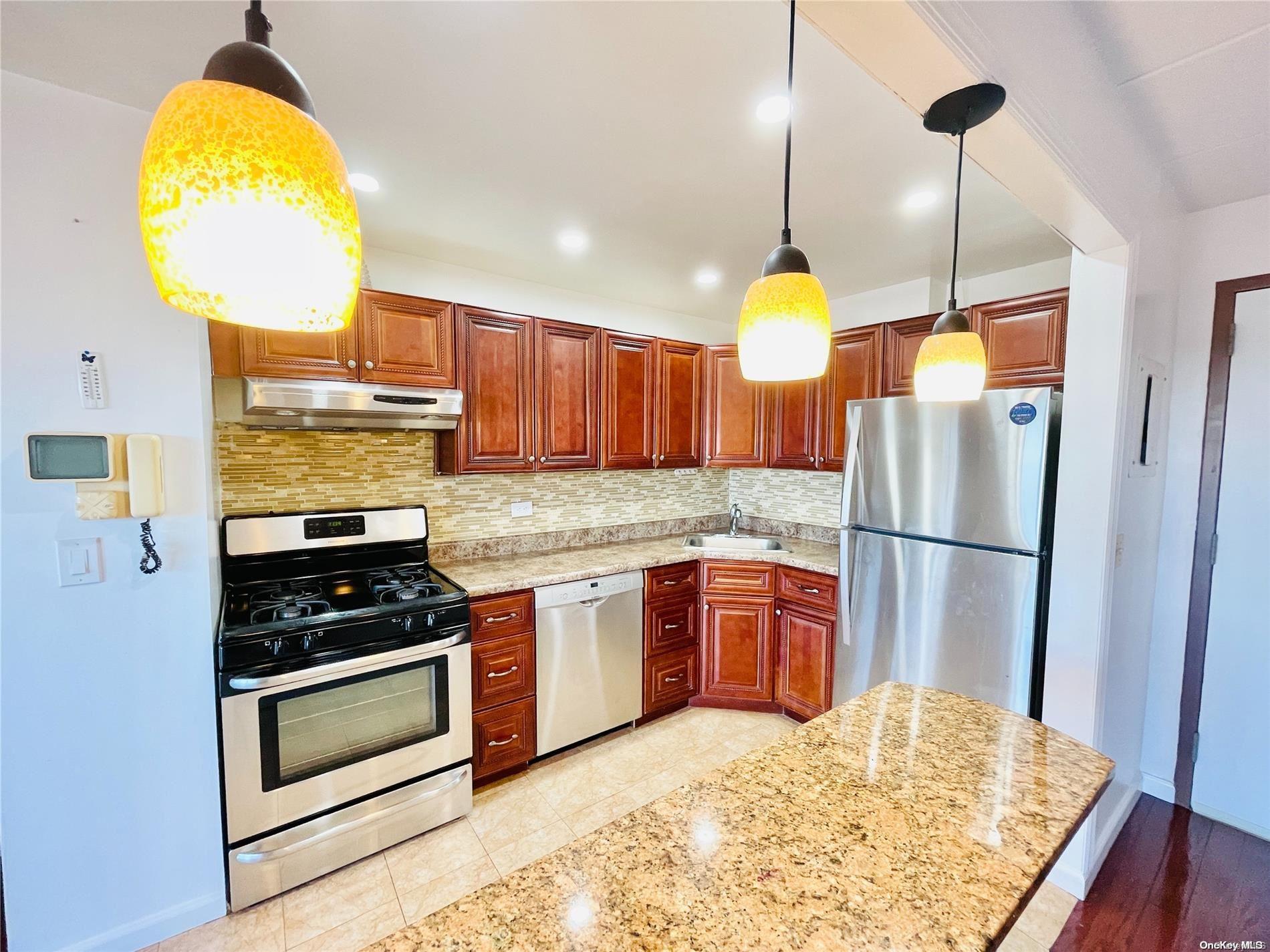 a kitchen with stainless steel appliances granite countertop a stove a refrigerator and a wooden floor