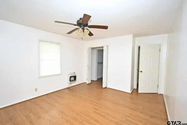 an empty room with windows and a ceiling fan