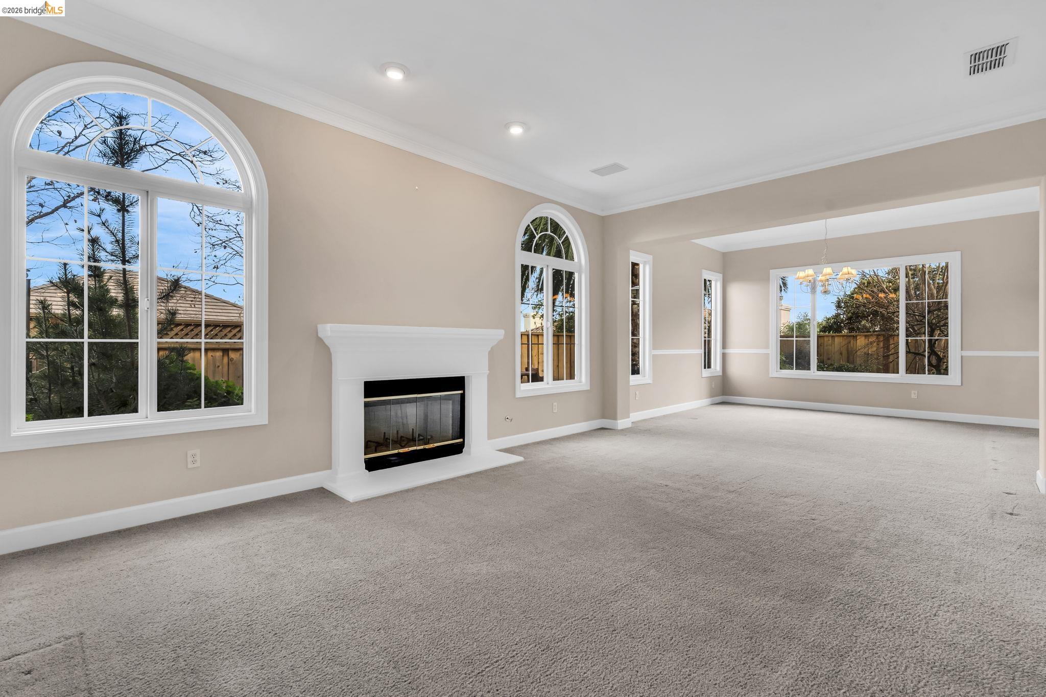 5 Circle E Ranch Place San Ramon, CA 94583 - Photo 14 of 60 Unfurnished living room with a glass covered fireplace, light carpet, hanging lights, crown molding, and plenty of natural light