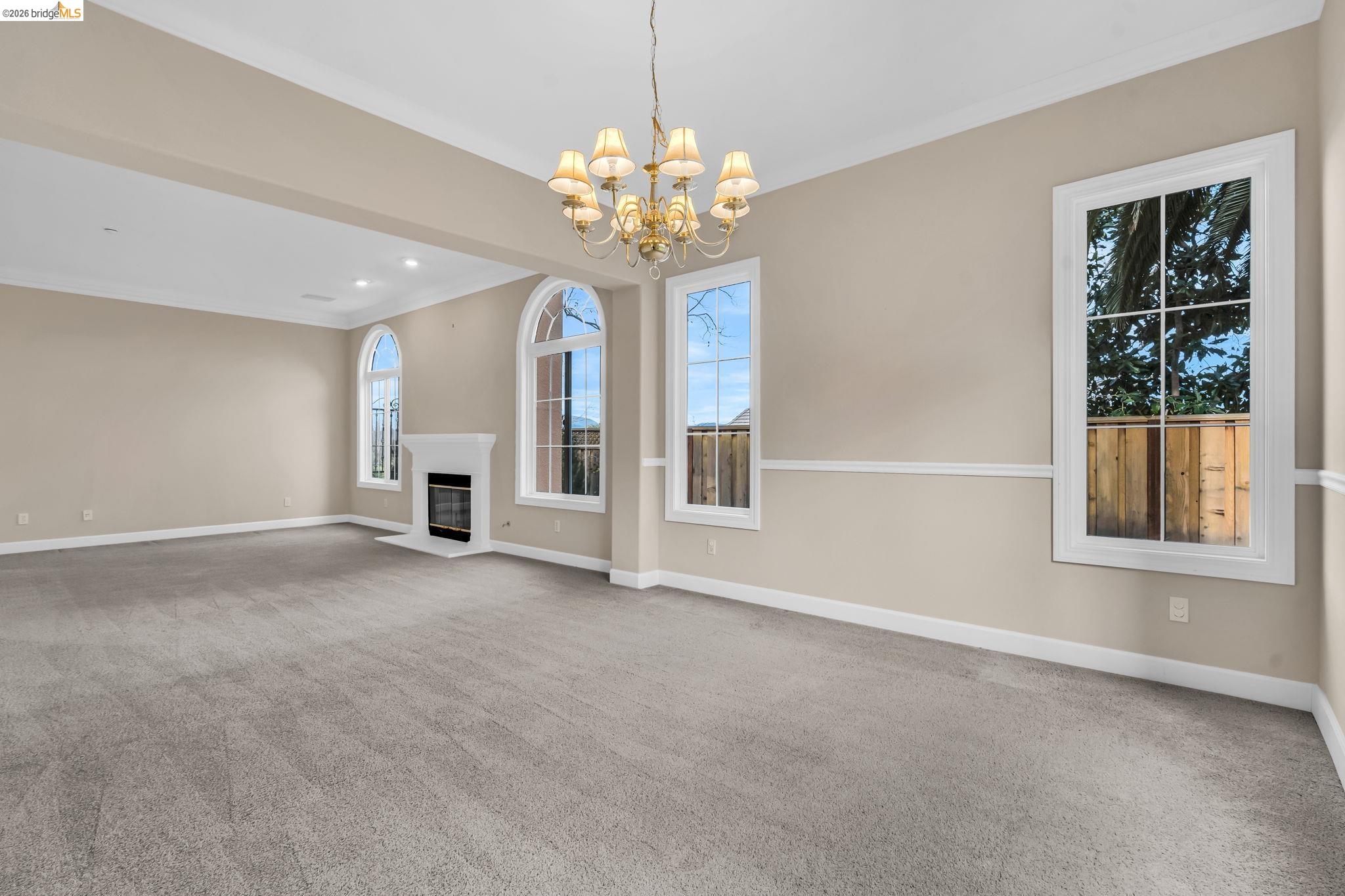 5 Circle E Ranch Place San Ramon, CA 94583 - Photo 17 of 60 Unfurnished living room featuring crown molding, carpet, a fireplace with flush hearth, and suspended lighting