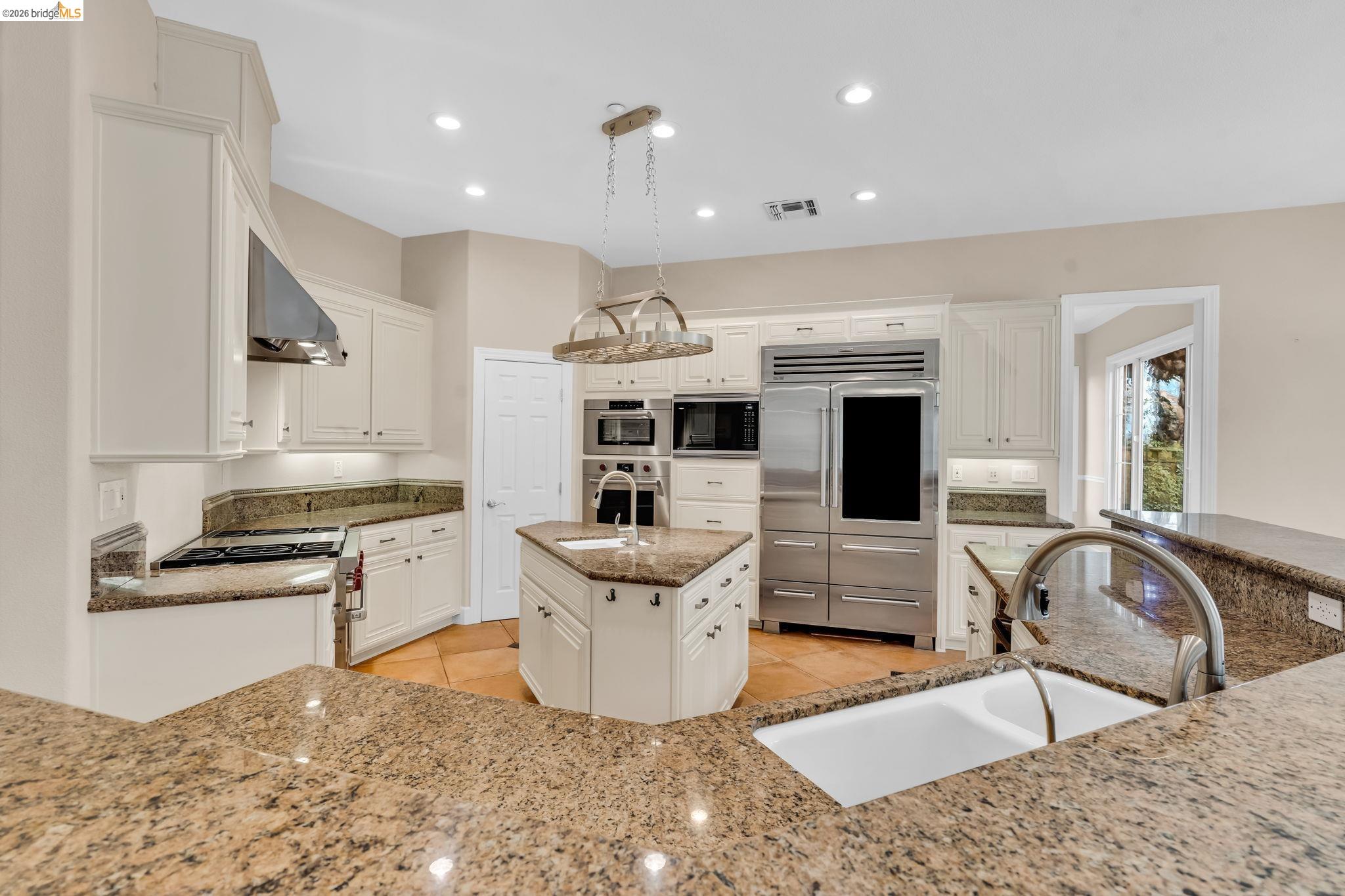 5 Circle E Ranch Place San Ramon, CA 94583 - Photo 50 of 60 Kitchen featuring built in appliances, white cabinets, a kitchen island with sink, and pendant lighting