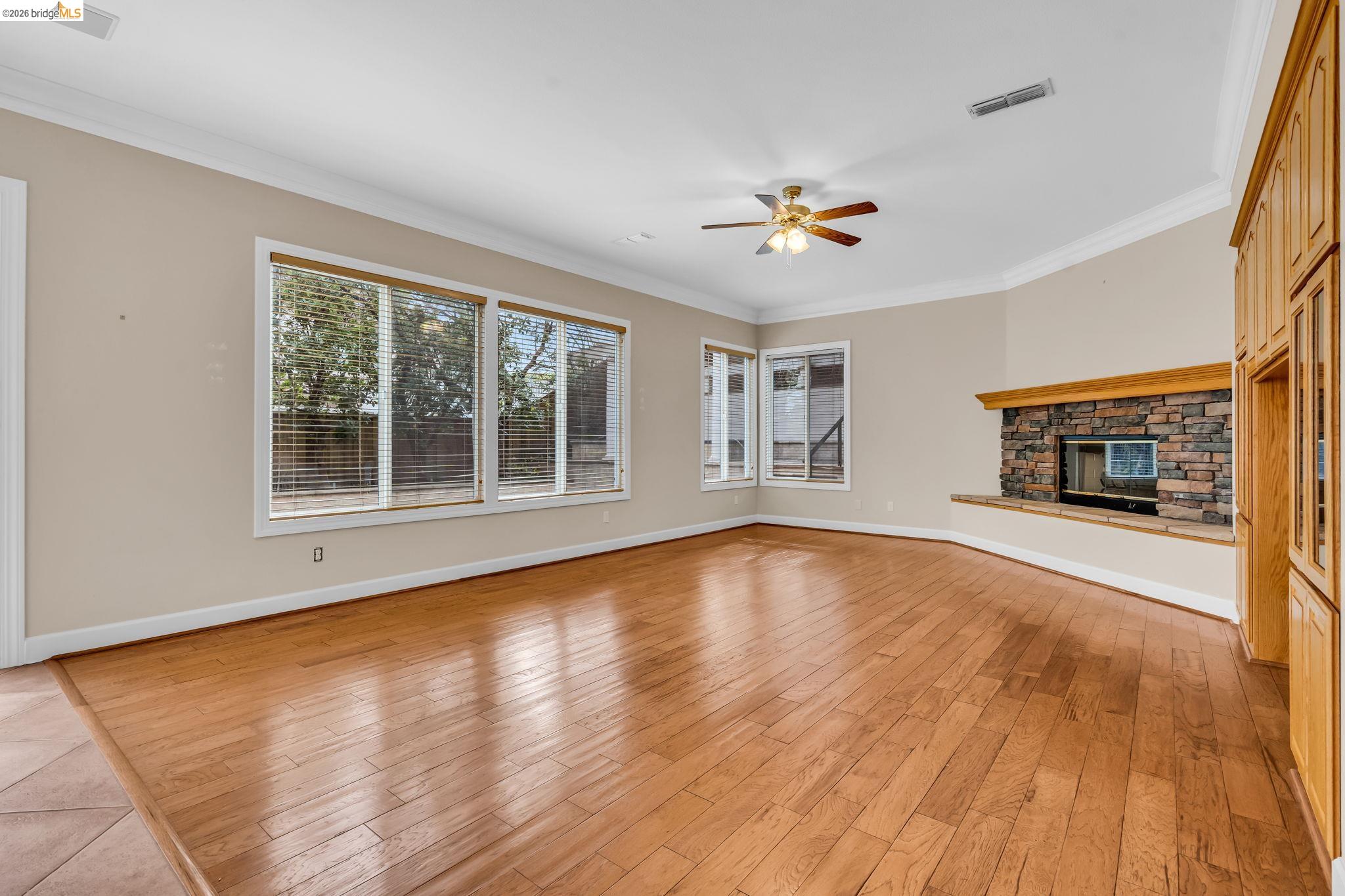 5 Circle E Ranch Place San Ramon, CA 94583 - Photo 53 of 60 Unfurnished living room featuring ornamental molding, a ceiling fan, light wood finished floors, and a stone fireplace