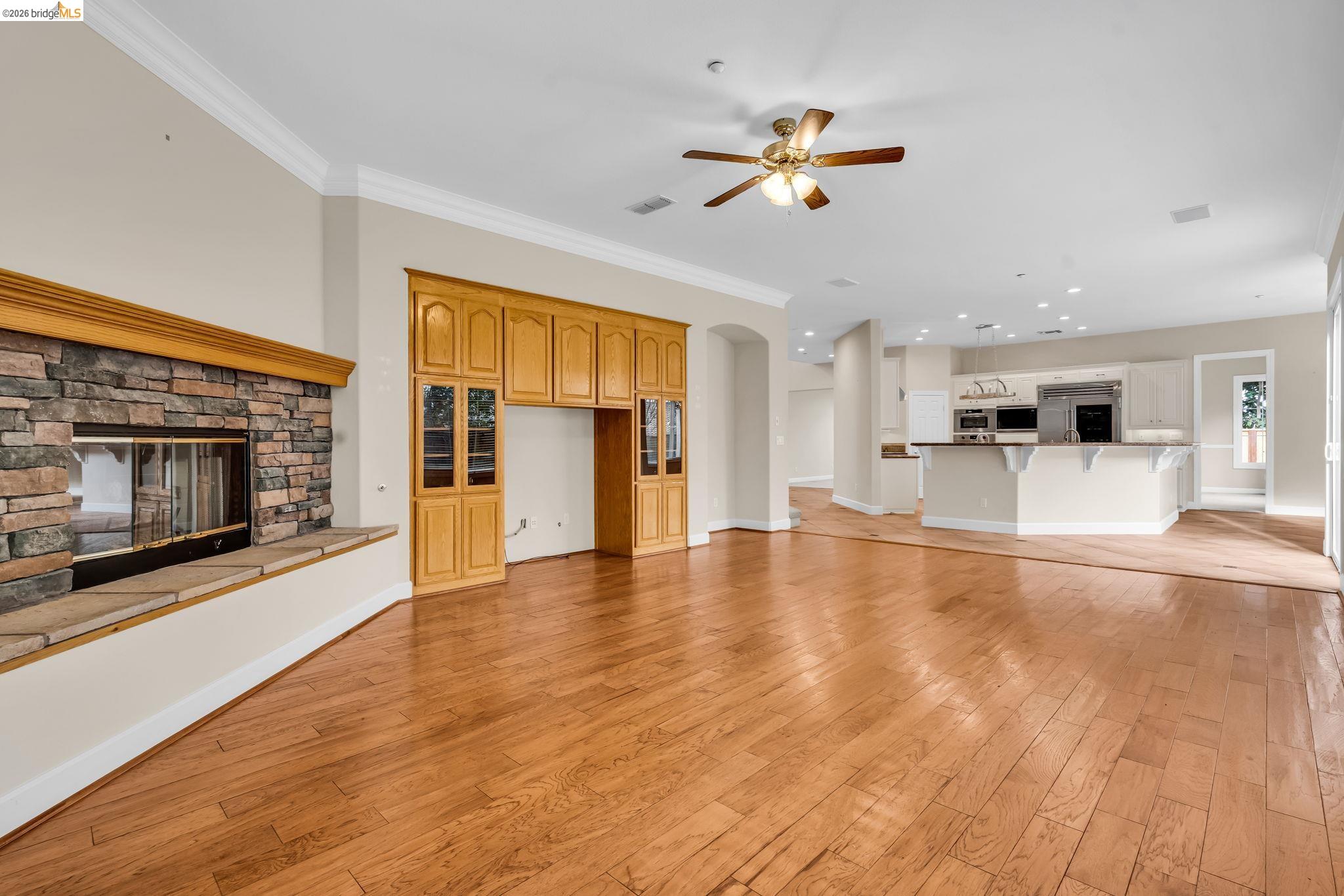 5 Circle E Ranch Place San Ramon, CA 94583 - Photo 54 of 60 Unfurnished living room with a stone fireplace, light wood finished floors, ceiling fan, crown molding, and recessed lighting
