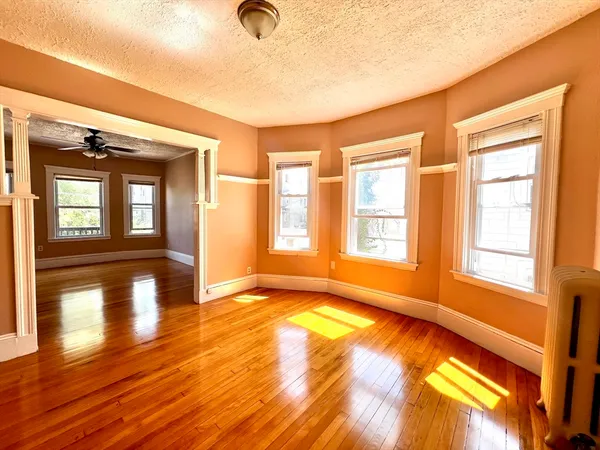 a view of an empty room with window and wooden floor