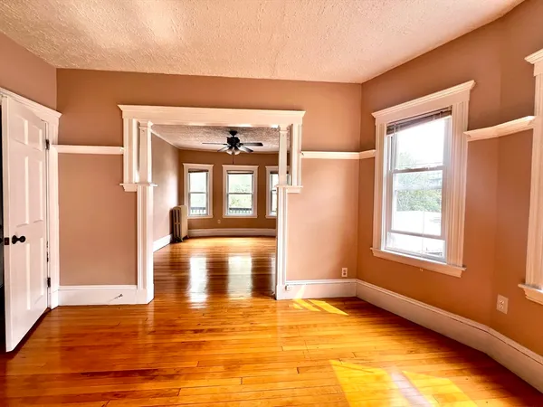 a view of an empty room with window and wooden floor