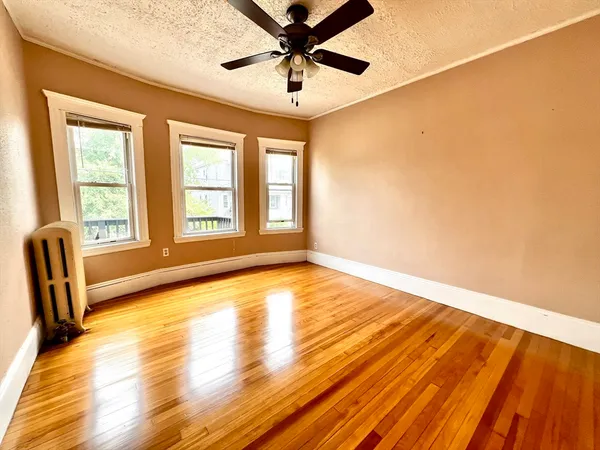 a view of an empty room with window and wooden floor