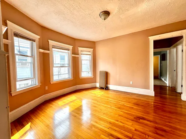 a view of an empty room with window and wooden floor