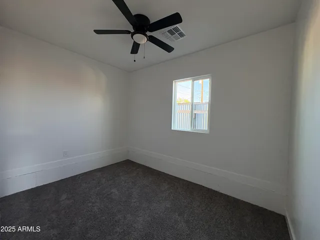 an empty room with a window and a fan