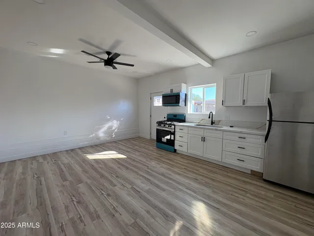 a kitchen with stainless steel appliances white cabinets and wooden floors