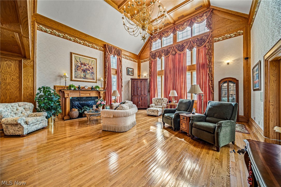 8801 Bunker Road Orwell, OH 44076 - Photo 10 of 50 Living area featuring high vaulted ceiling, hardwood / wood-style floors, wallpapered walls, a high end fireplace, and a chandelier