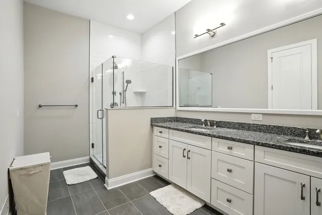 a bathroom with a granite countertop sink a mirror and a shower