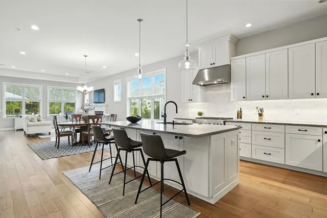 a kitchen with stainless steel appliances granite countertop sink stove and white cabinets with wooden floor