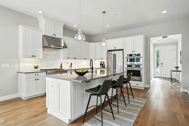 a kitchen with stainless steel appliances kitchen island granite countertop a table chairs refrigerator and microwave