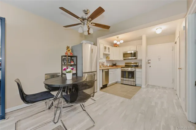 a kitchen with stainless steel appliances kitchen island granite countertop a dining table chairs and a refrigerator