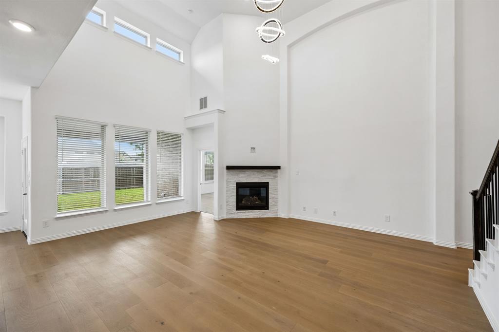 1303 Wheelwright Drive Forney, TX 75126 - Photo 13 of 39 Great room featuring wood-finish flooring, a corner fireplace with a white stone surround, and an integrated mantle
