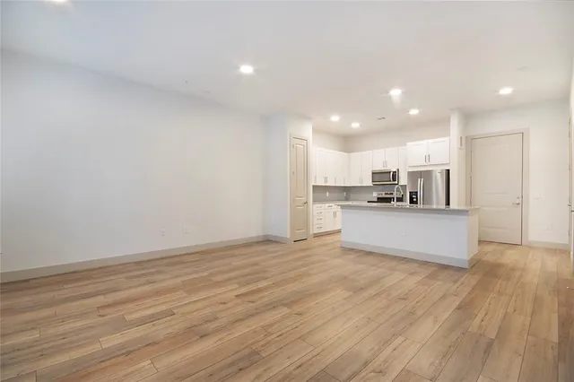 a view of kitchen with kitchen island wooden floor center island and stainless steel appliances