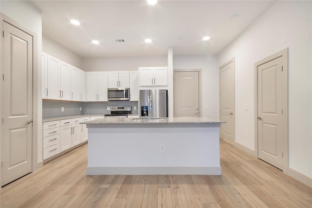 4700 West Spring Creek Parkway, Unit 10102 Plano, TX 75024 - Photo 8 of 20 a large kitchen with stainless steel appliances granite countertop a stove a sink and white cabinets