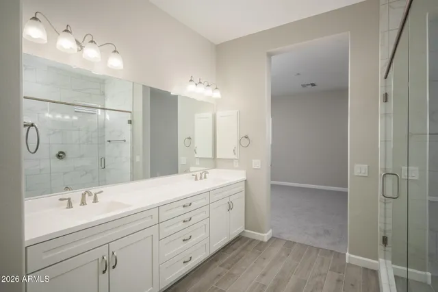 a spacious bathroom with a double vanity sink a large mirror and shower