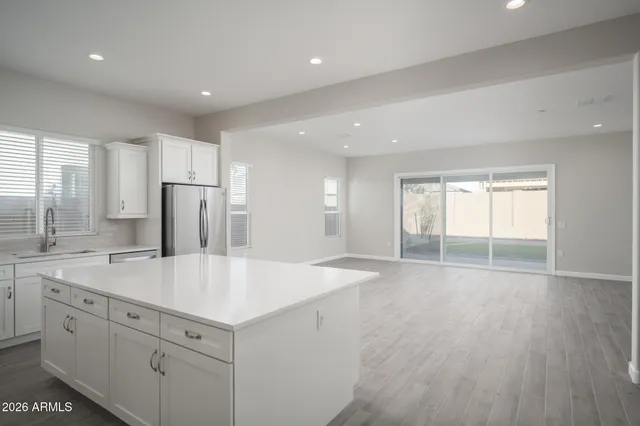 a view of kitchen with center island wooden floor and refrigerator