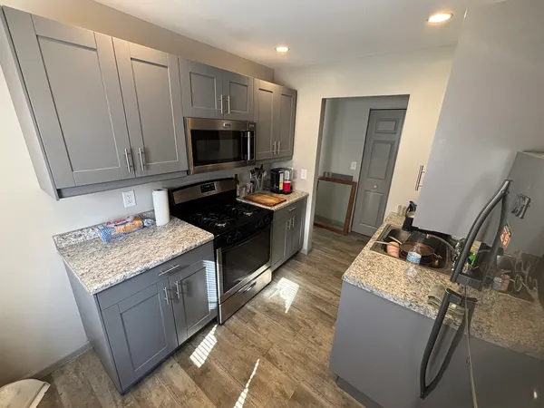 a kitchen with granite countertop a sink stove and refrigerator