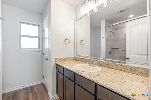 a bathroom with a granite countertop sink and a mirror